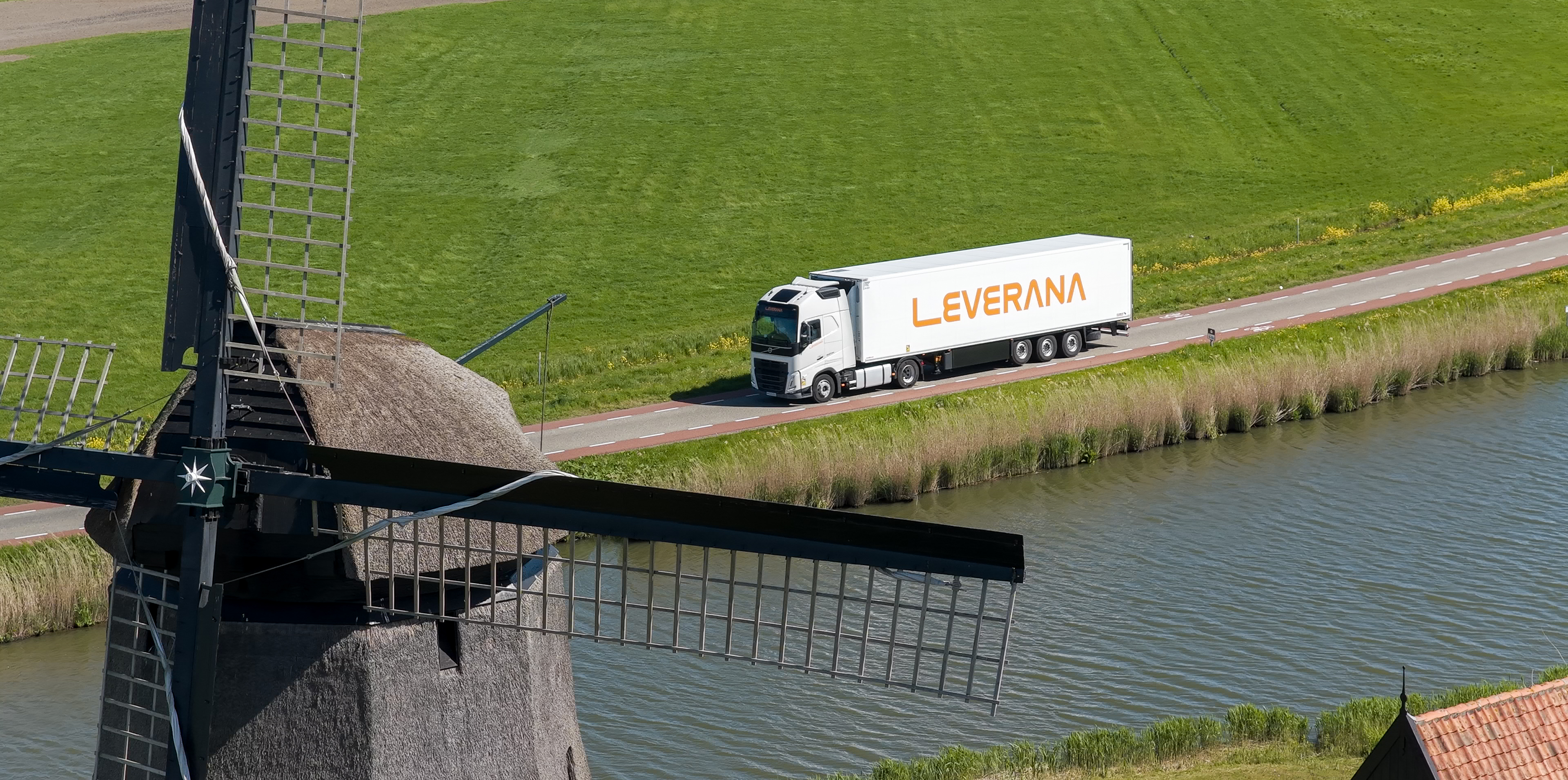 Leverana refrigerated truck passing a Dutch windmill along a canal